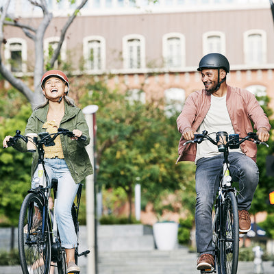 Two riders on e-bikes riding through the city